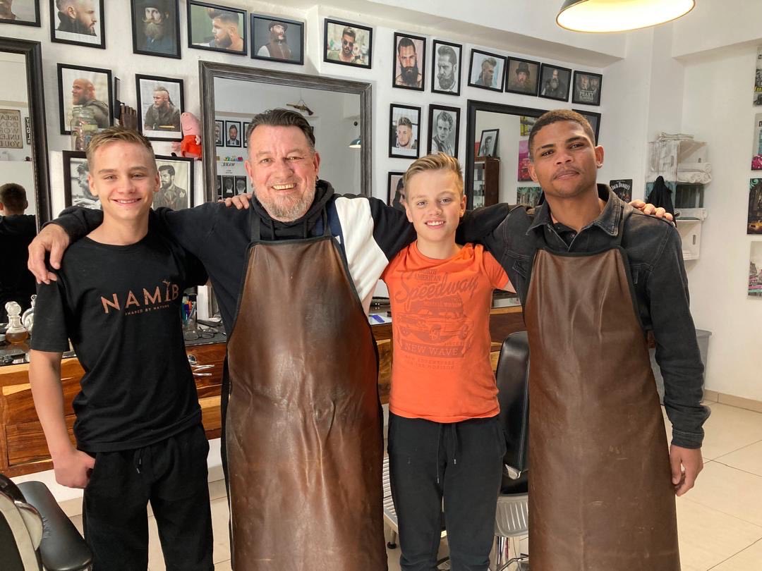 The Paul's Barbershop team with a young client